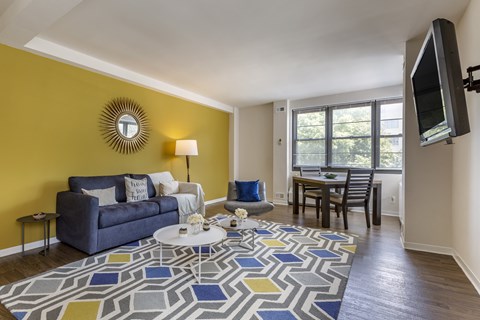 A living room with a blue couch, a white coffee table, and a flat screen TV mounted on the wall.